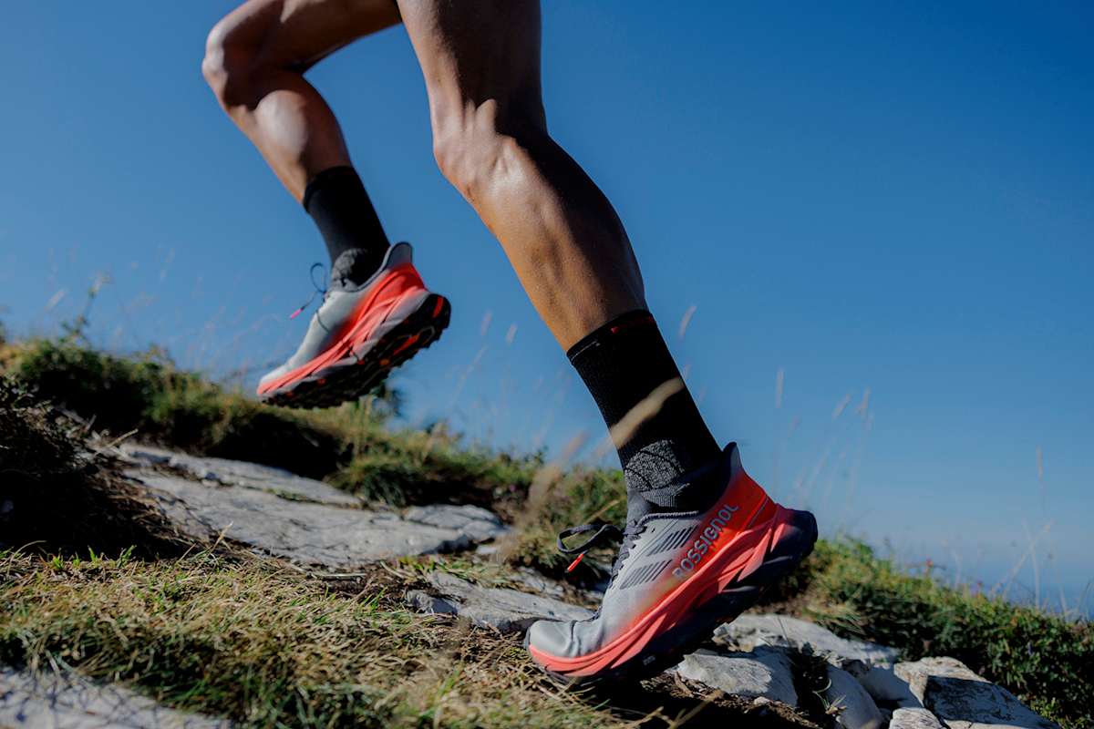 Zu sehen sind die Beine eines Läufers, welcher Rossignol Laufschuhe trägt, während er einen felsigen Weg hinaufläuft.