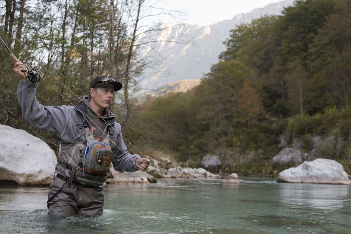 Der Angler im türkisen Wasser wirft die Rute aus.