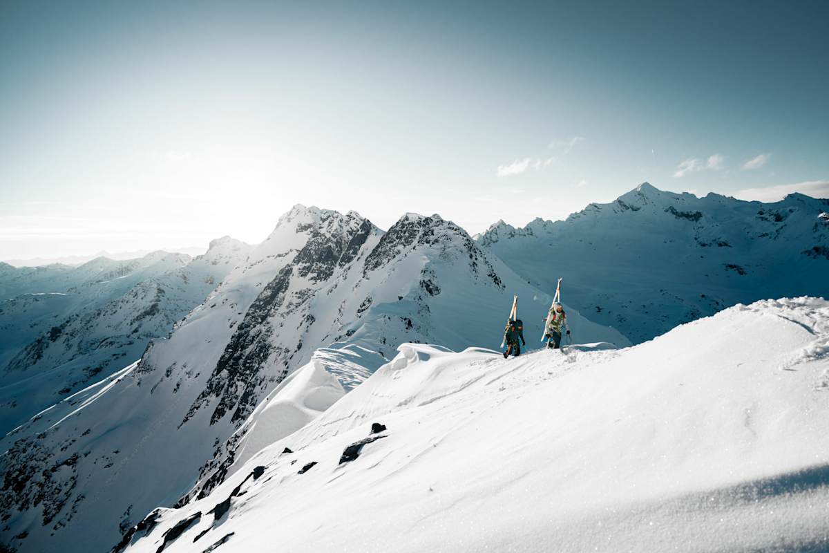 Zwei Skitourengeher vor einem weißen Bergpanorama