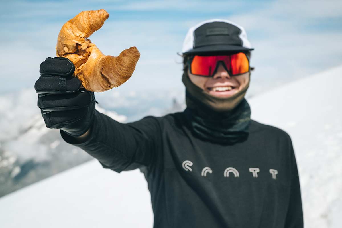 Tobias Renggli auf seiner Tour zu den höchsten Punkten aller Schweizer Kantone – mit einer Vorliebe für knusprige Gipfeli, das er auf dem Bild in die Kamera.