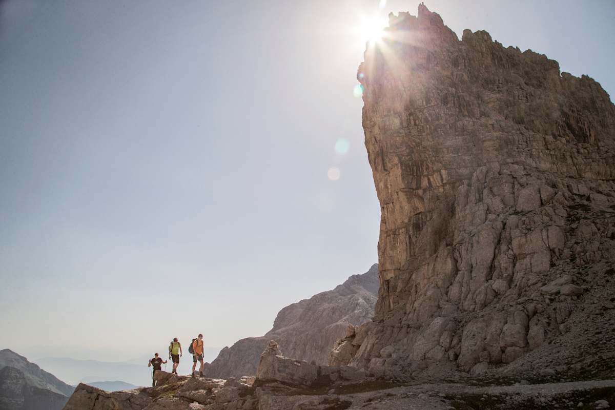 Drei Wanderer am Weg auf einen schroffen Dolomitengipfel.