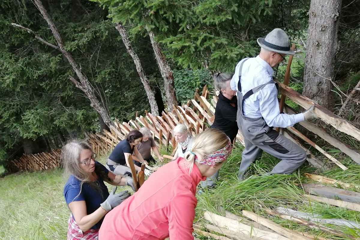 Menschen errichten gemeinsam einen Zaun.