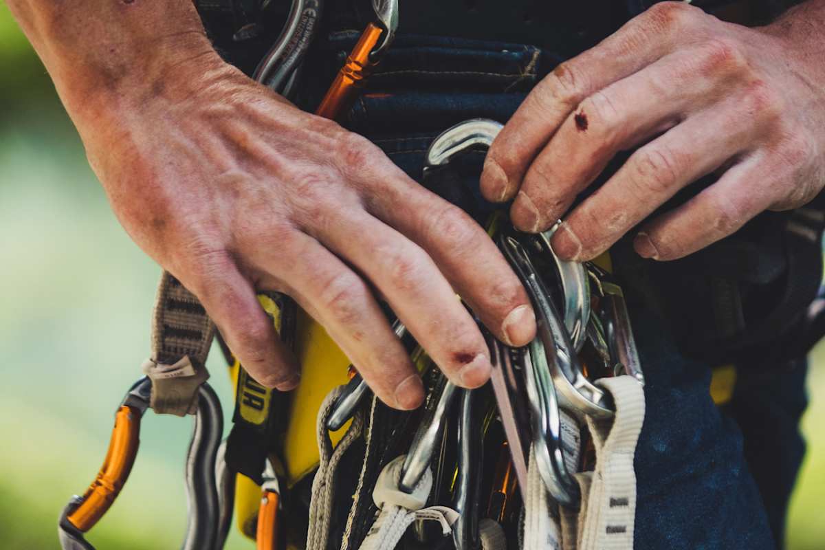 Duzende Karabiner baumeln am Klettergeschirr. 