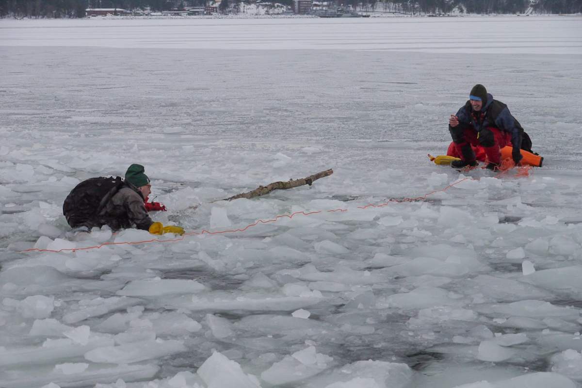 Links ein ins Eis eingebrochener Skater, rechts ein Skater mit Rettungsleine auf sicherer Oberfläche