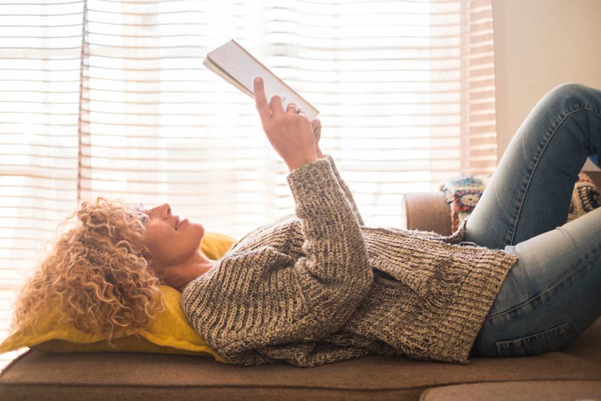 Frau liest Buch im Liegen