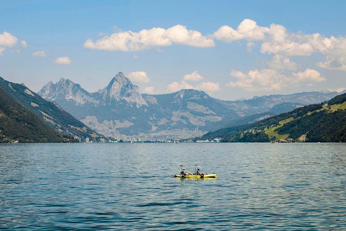 Zwei Paddler am See, dahinter atemberaubendes Bergpanorama.