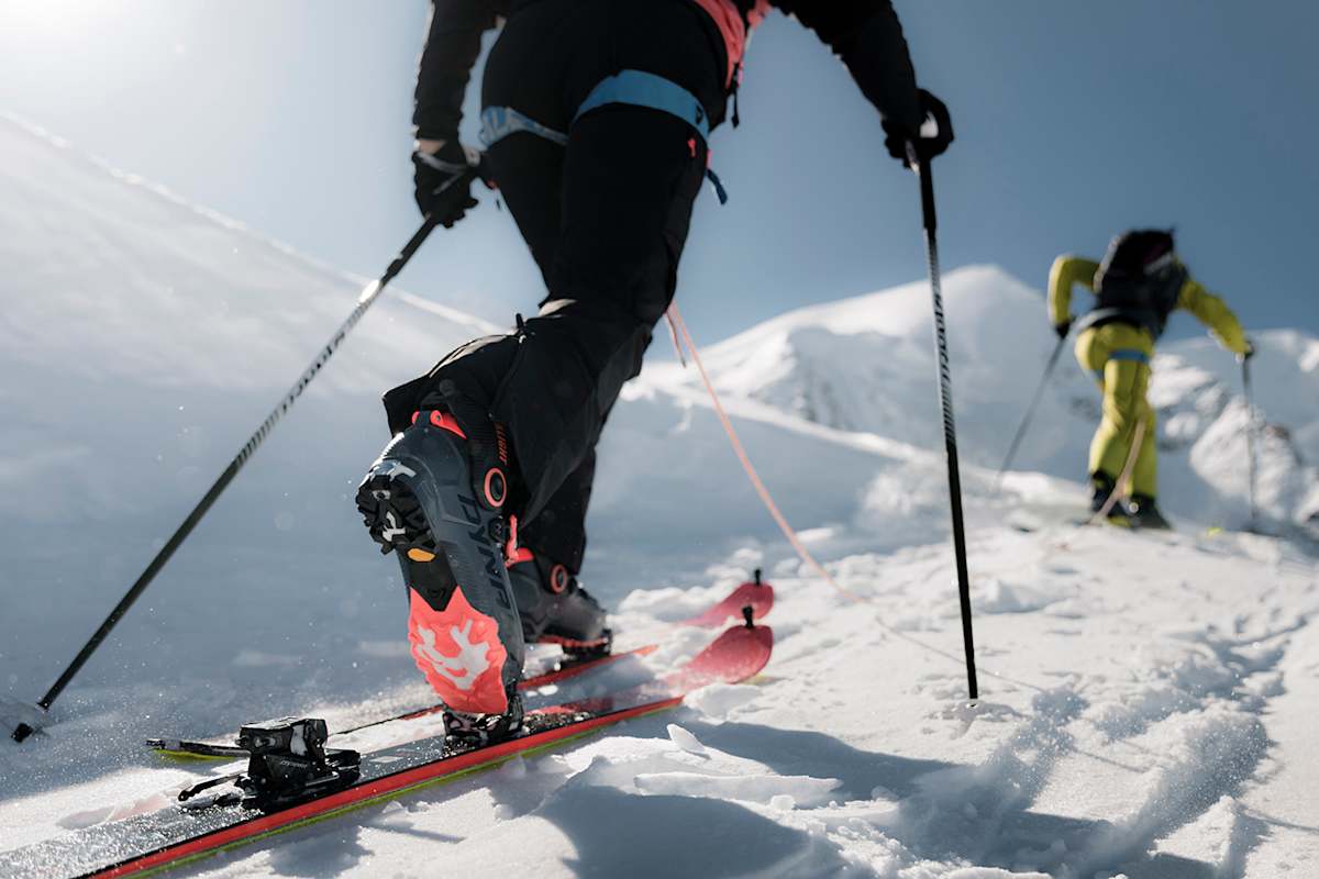 Skitourengeher mit Dynafit Blacklight-Ausrüstung beim Aufstieg durch tiefen Schnee im Hochgebirge bei Sonnenschein.