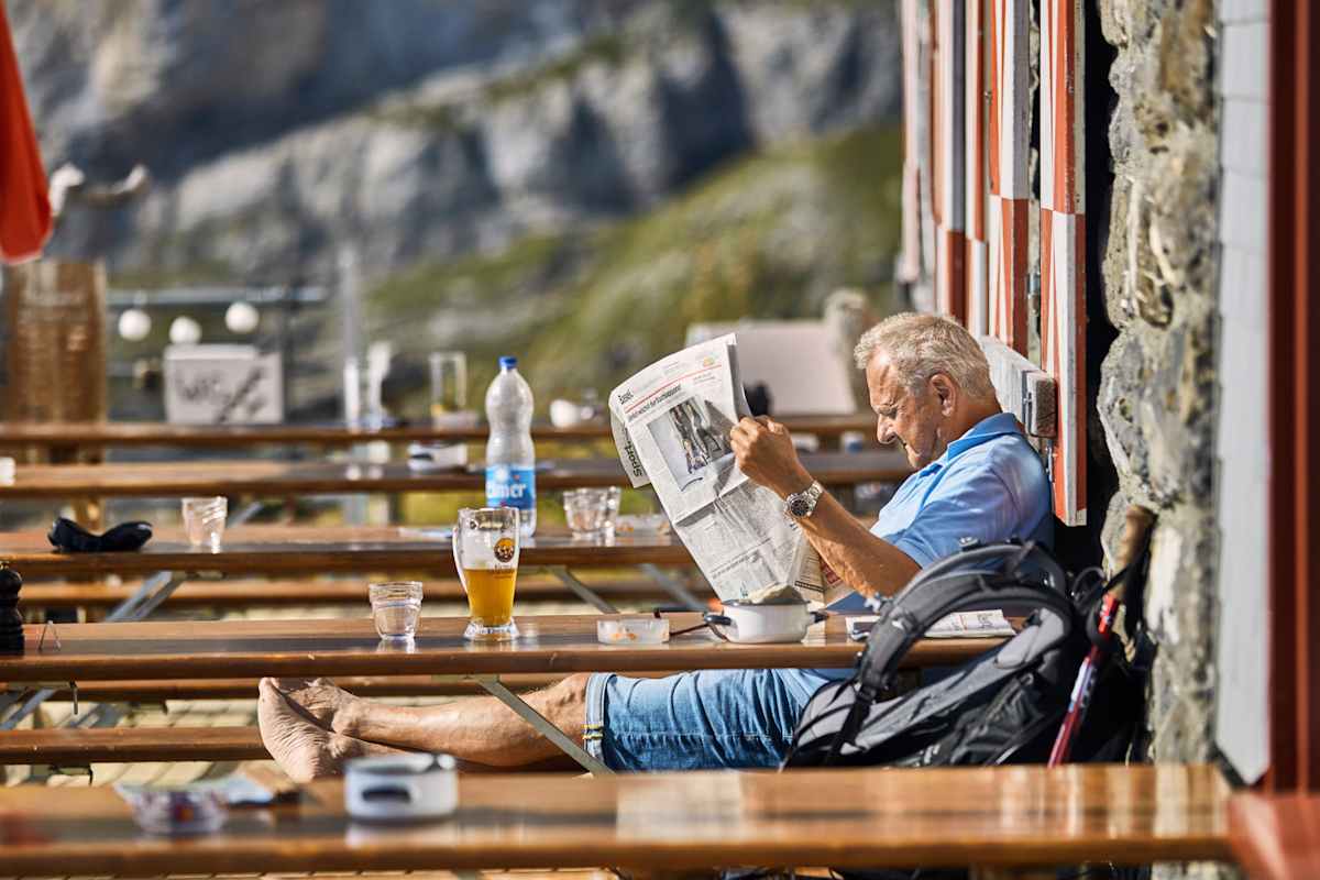 Ei Mann ließt Zeitung und genehmigt sich ein Bier.