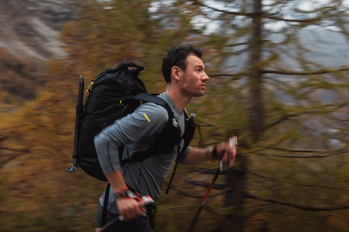 Ein Sportler im Wald mit Walkingstecken und Rucksack.