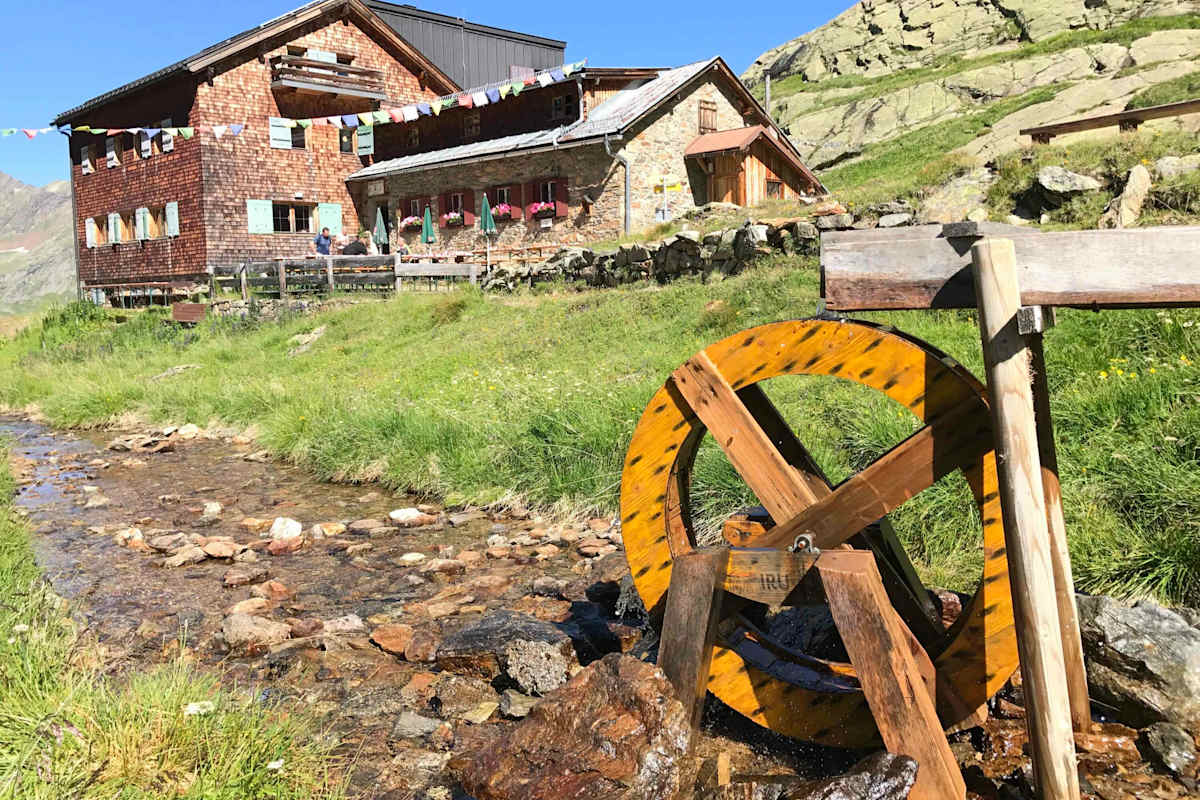 Viele Hütten gewinnen ihre Energie aus Kleinwasserkraftwerken. Symbolhaft mit diesem schönen Holzwasserrad vor der Edmund-Graf-Hütte im Verwall dargestellt.