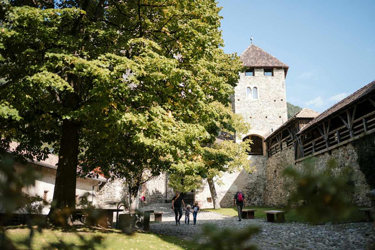Das Schloss tirol in Südtirol mit Bäumen und Wanderern