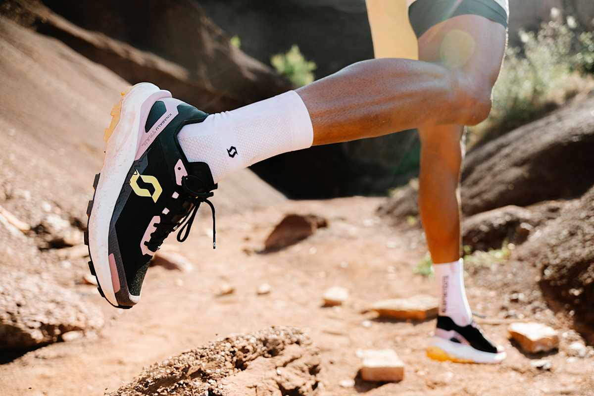 Zu sehen ist der Unterkörper eines Läufers der durch eine steinige Landschaft läuft die Kinabalu Trailrunning-Schuhe von Scott dabei trägt.