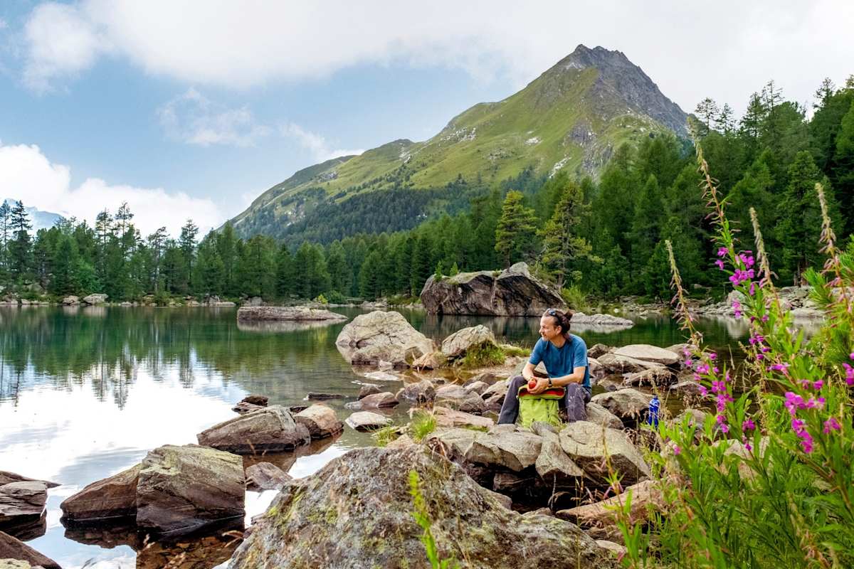 Ein Wanderer ruht sich am Wasser aus.