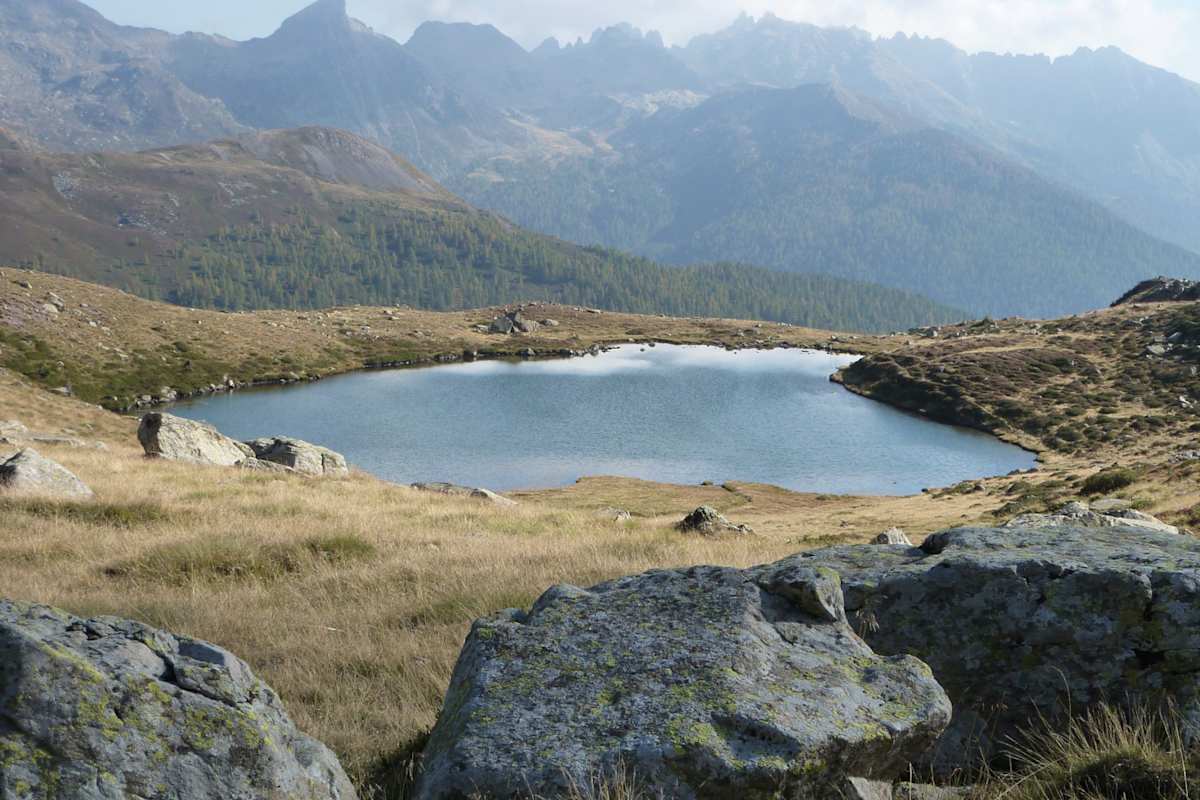 Ein einsamer Bergsee, im Hintergrund eine zackige Gebirgskette.