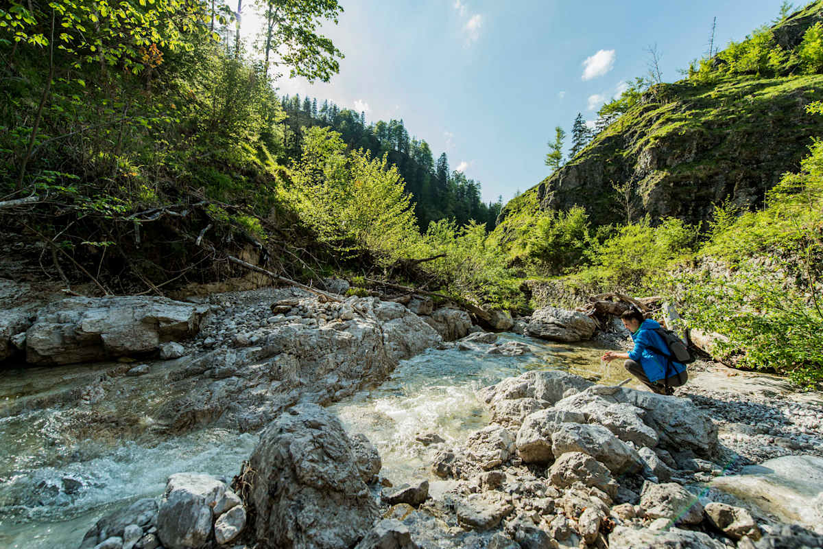 Eine Frau macht eine kurze Rast am Bach.