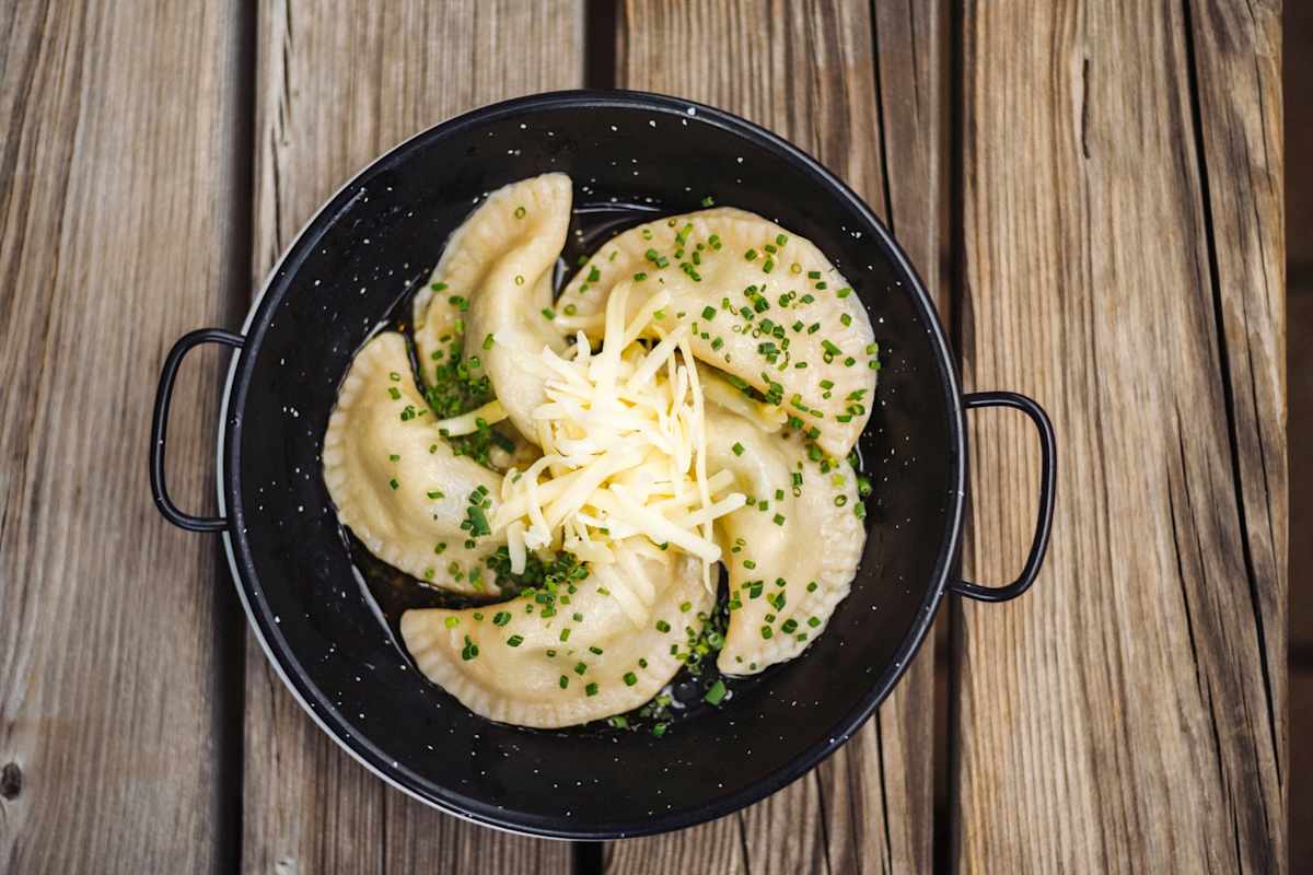 Frische Schlutzkrapfen mit geriebenem Käse in einer Rein serviert.