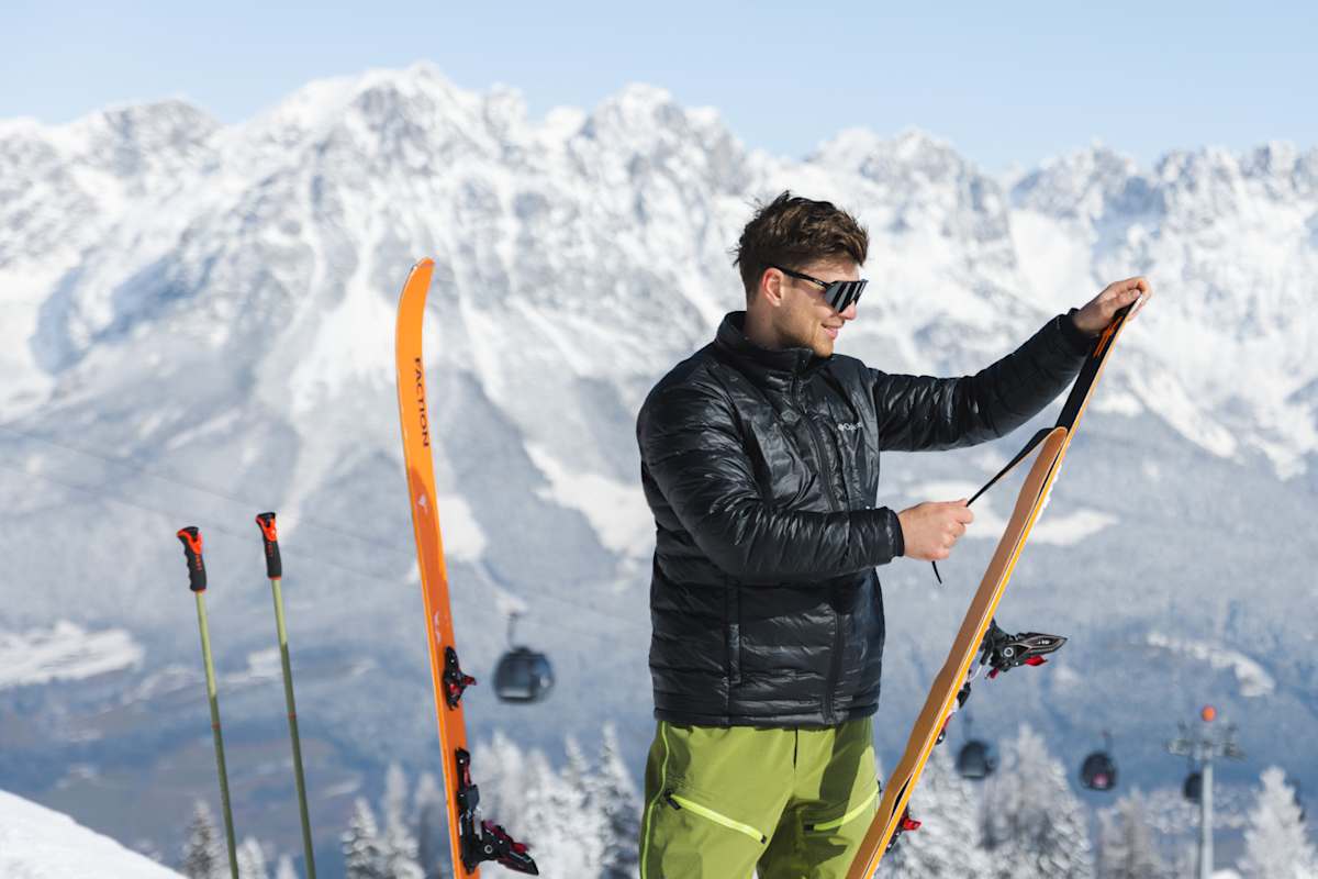 Ein Skitourengeher zieht in der Region Wilder Kaiser seine Felle von den Tourenskiern. Im Hintergrund die markante, tief verschneite Felskulisse des Wilden Kaisers.