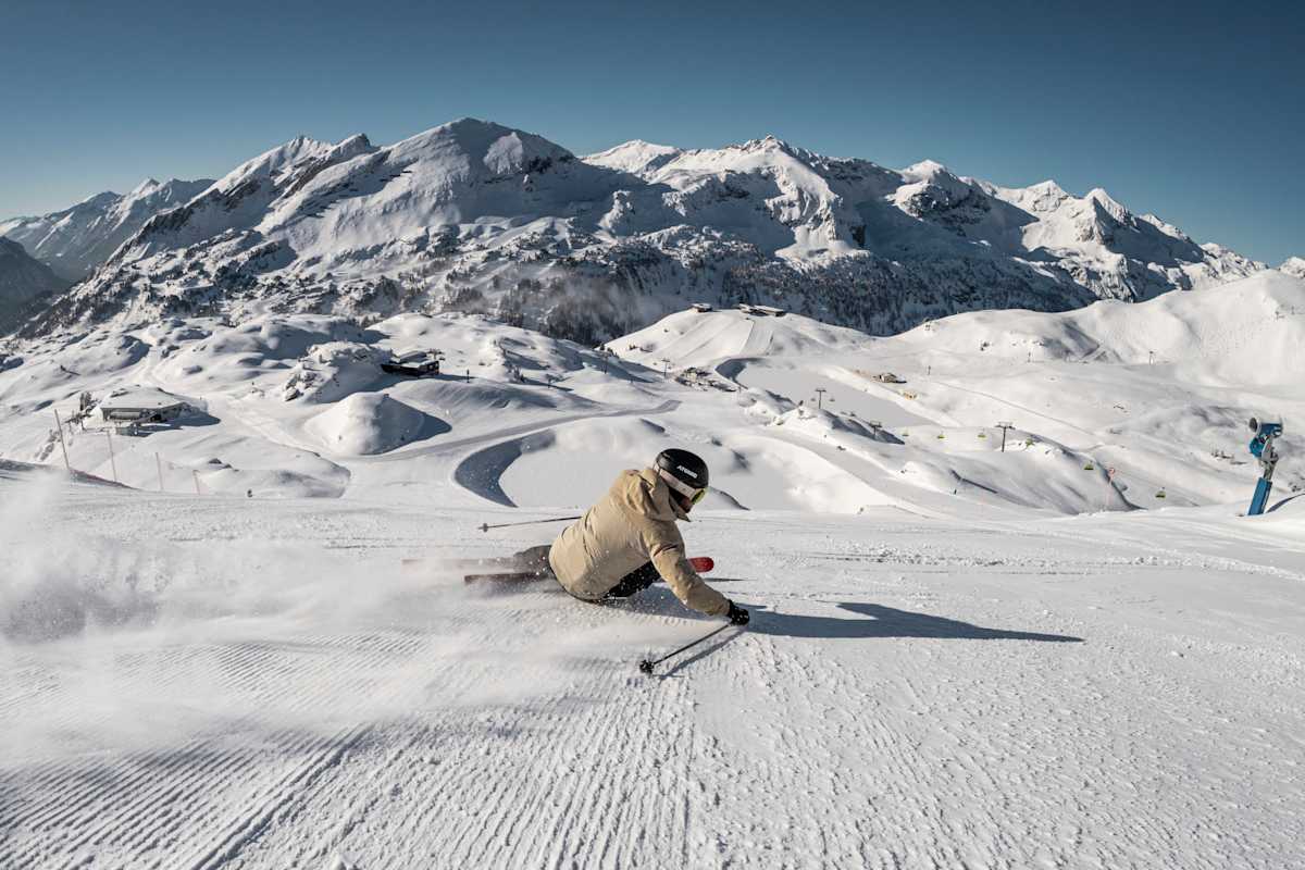 Ein Skifahrer carvt in hohem Tempo über die Pisten von Obertauern.