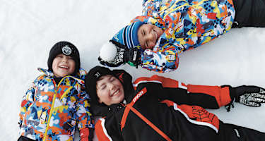 Drei Kinder liegen im Schnee in See.