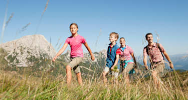 Eine Familie wandert auf einer Alm.