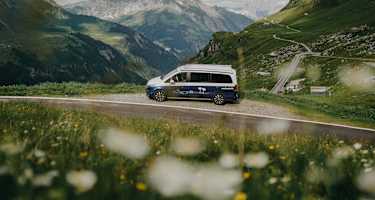 Ein Roadsurfer-Campervan steht am Straßenrand, Blick in die Berge