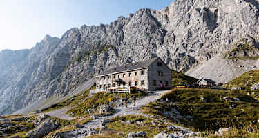 Blick auf die Lamsenjochhütte, die vor gewaltigen Felswänden im Karwendel steht