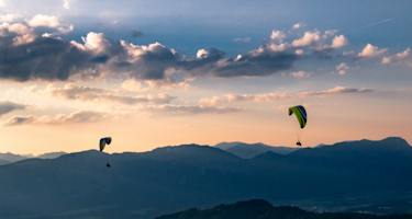 Zwei Personen paragleiten über ein Tal in der Wildschönau.