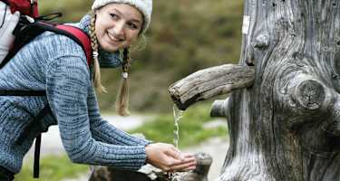 Wanderin schöpft Wasser aus einem Brunnen