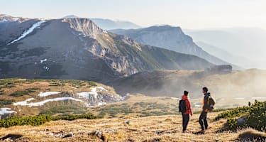 Zwei Wanderer stehen im Herbst auf dem Raxplateau und blicken in die Ferne
