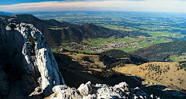 Blick vom Gipfel auf die dunklen Kaisersäle (links), Aschau und das Alpenvorland.