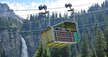 Die Luftseilbahn von Äsch zur Oberalp mit dem Stäubiwasserfall im Hintergrund