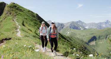 Zwei Wanderinnen gehen auf einem Grat.