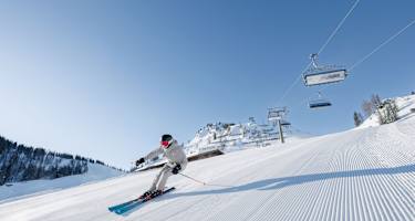 Ein Skifahrer carvt auf einer frisch präparierten Piste auf der Hermann Maier Tour im Snowspace Salzburg.