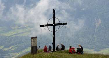 Wanderer geniessen den Gipfel des Gnipen mit dem Gipfelkreuz.