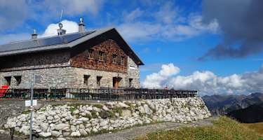 Eine Berghütte vor alpiner Kulisse.