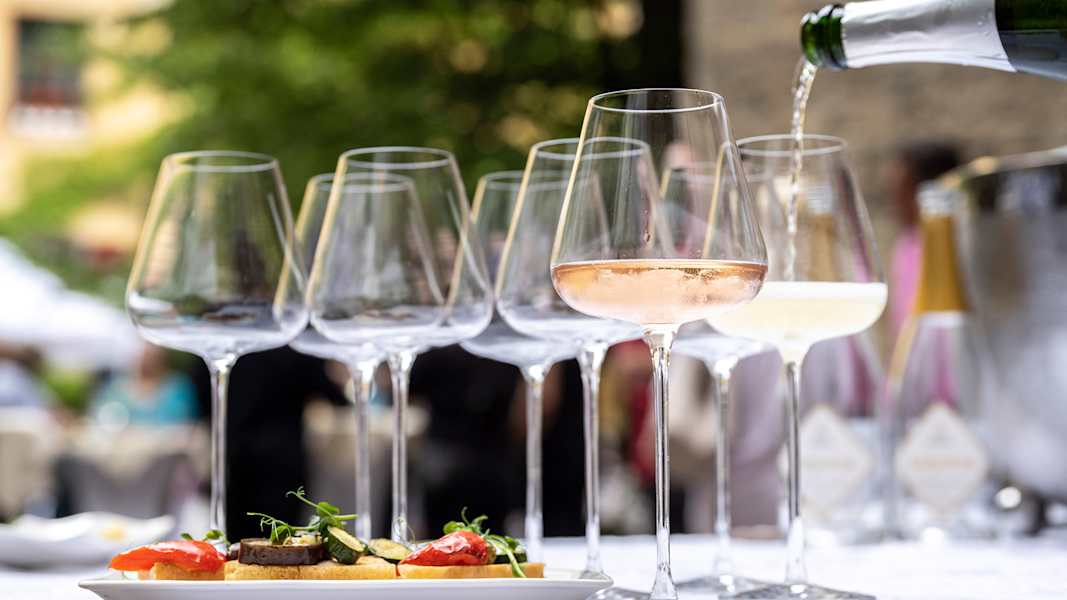 Bei einer sommerlichen Veranstaltung werden zu feinen Häppchen edle Schaumweine angeboten.