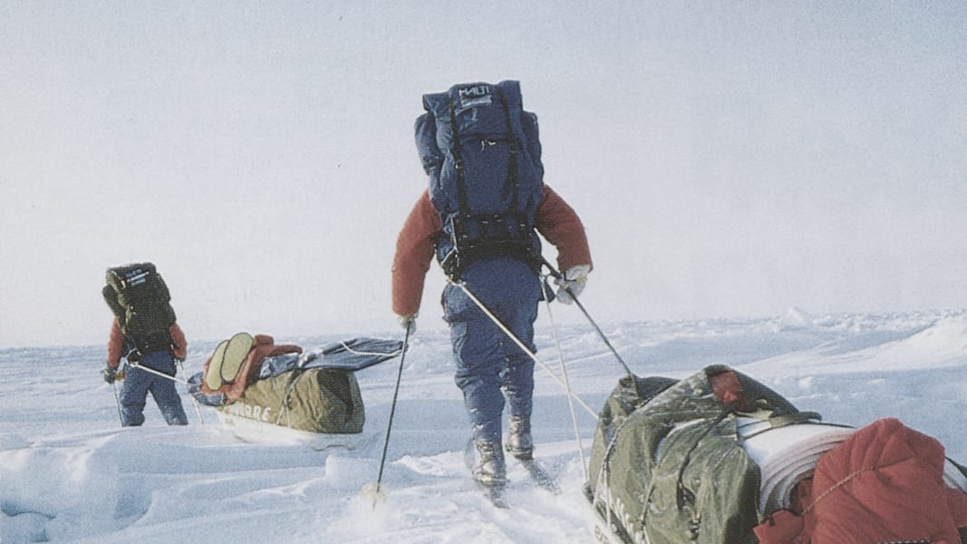 Zwei ausgerüstete Personen durch Schnee und Eis mit ihrer Ausrüstung.