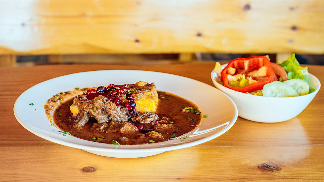 Ein Teller mit Gulasch und daneben ein Salat im Gasthaus.