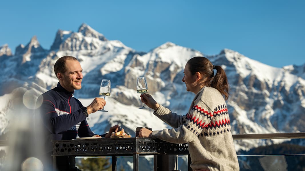 Ein Paar im Winter mit einem Glas Wein in einer Skihütte in den Bergen