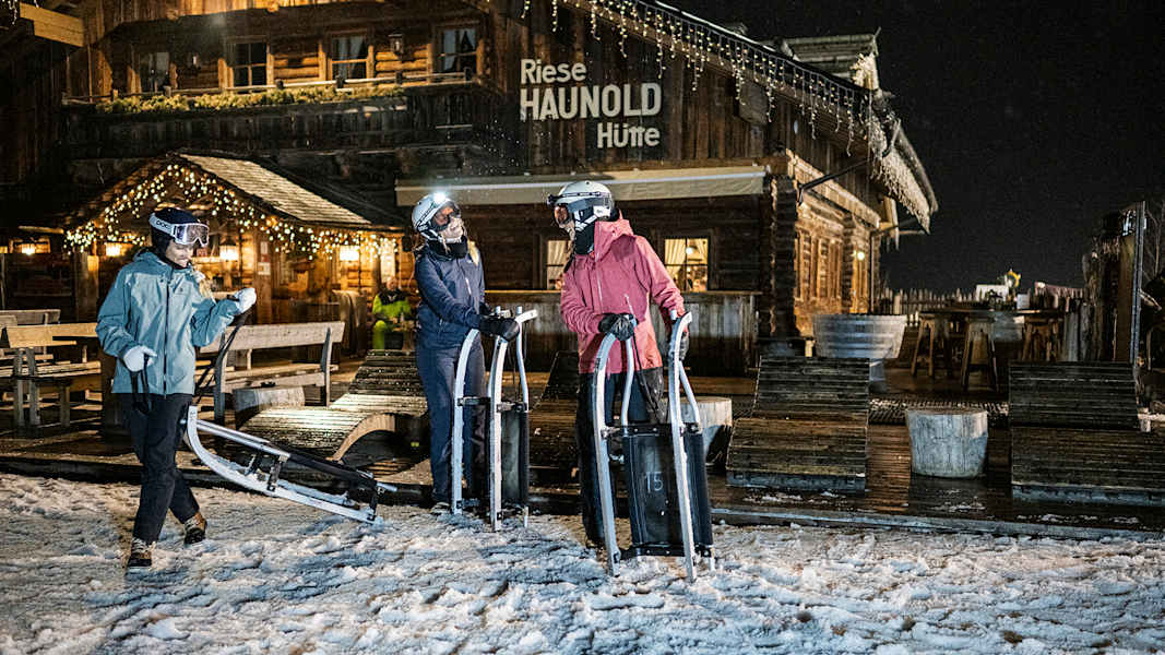 drei damen holen sich eine rodel im dunkeln und machen sich für eine nachtrodelfahrt bereit