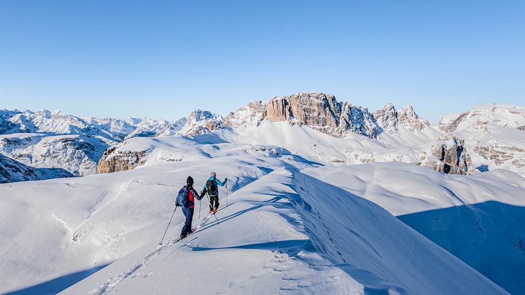 zwei skitourengeher auf dem weg zur bergspitze, die 3 zinnen sind im hintergrund