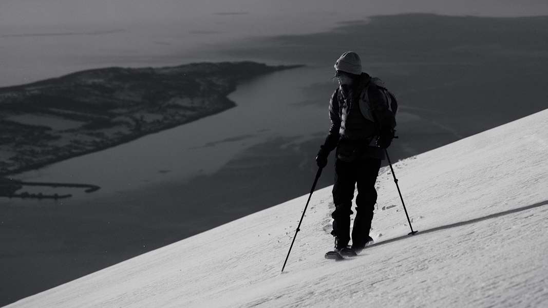 Skitourengeher vor Fjord und schneebedeckten Bergen in Nord-Norwegen.