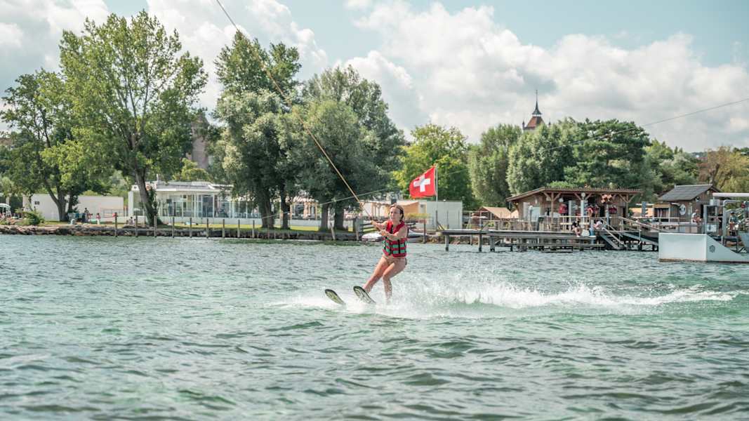 Eine Wasserskifahrerin wird von einem Automaten an einer Leine gezogen.