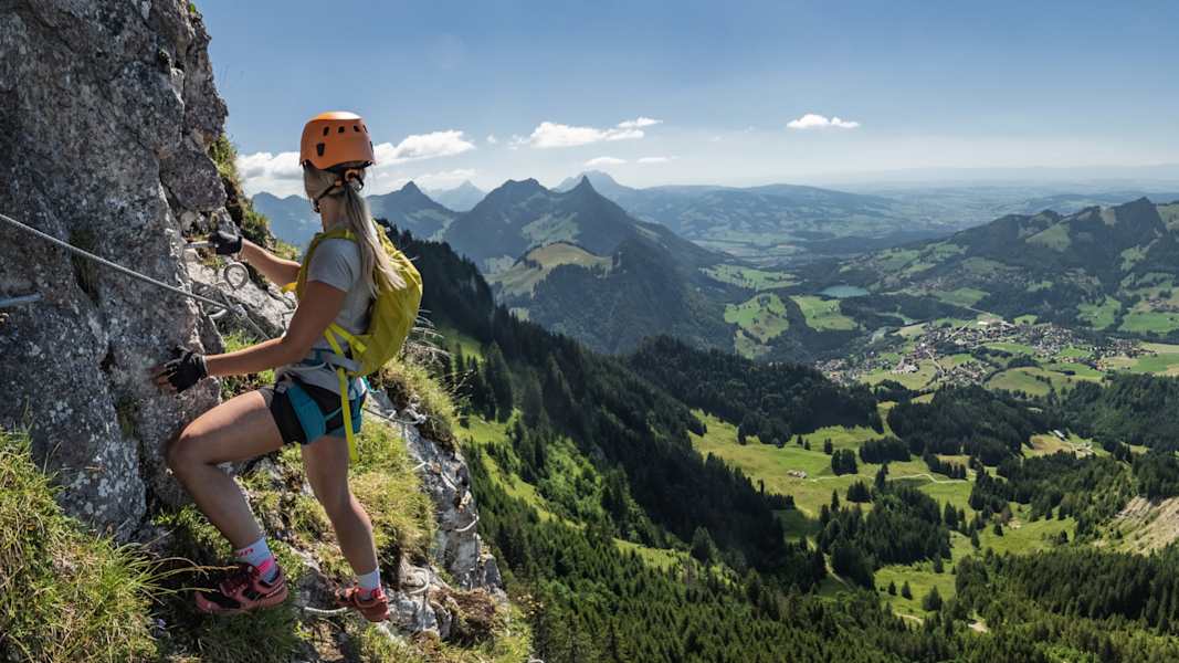 Eine Klettersteiggeherin genießt in der Via Ferrata von Charmey die Aussicht.