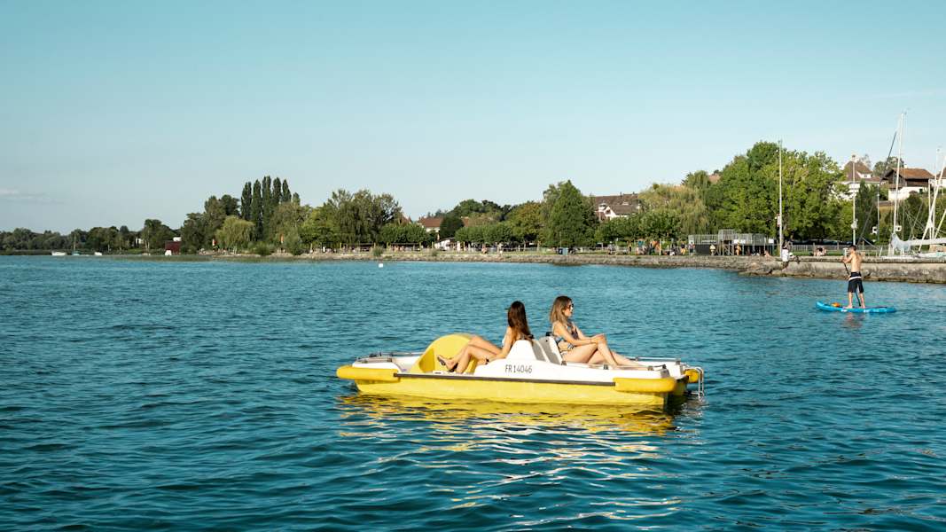 Zwei Frauen fahren mit einem Pedalo über den Murtensee.