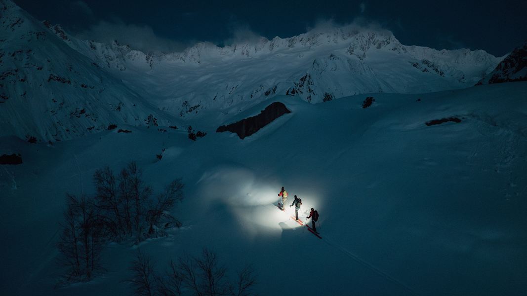 Drei Skitourengeher gehen in der Dunkelheit eine Tour in den Schweizer Alpen.