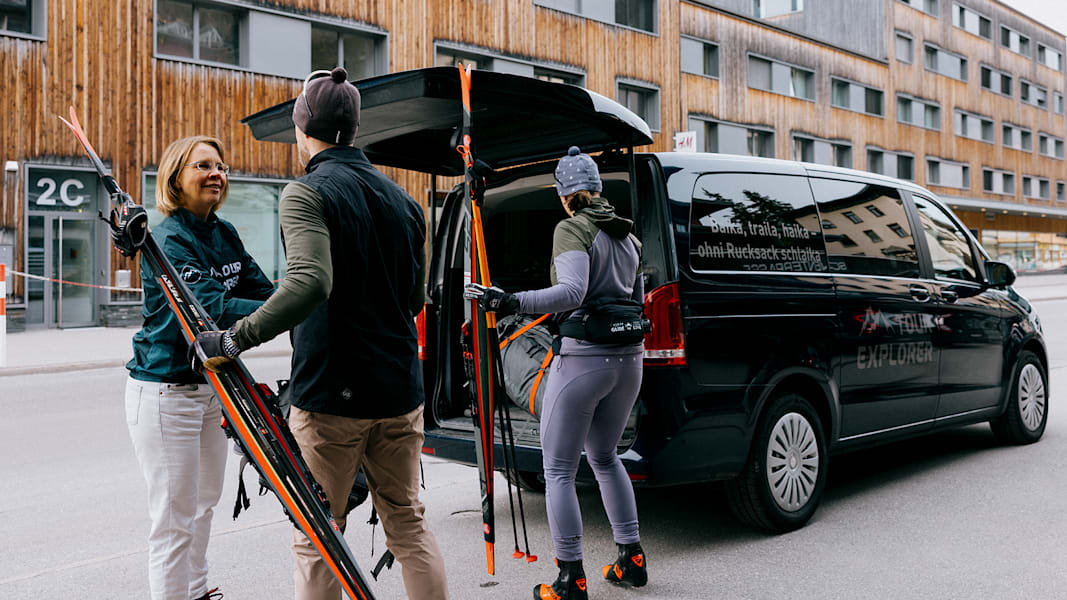 Vor dem Hotel räumen die zwei Sportler den Van ein, um Skilanglaufen zu gehen in der Schweiz.