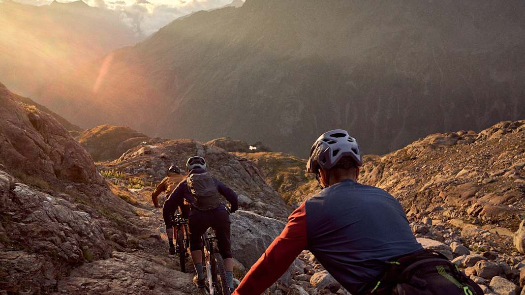 Drei Radfahrer fahren der Sonnen beim Sonnenuntergang entgegen.