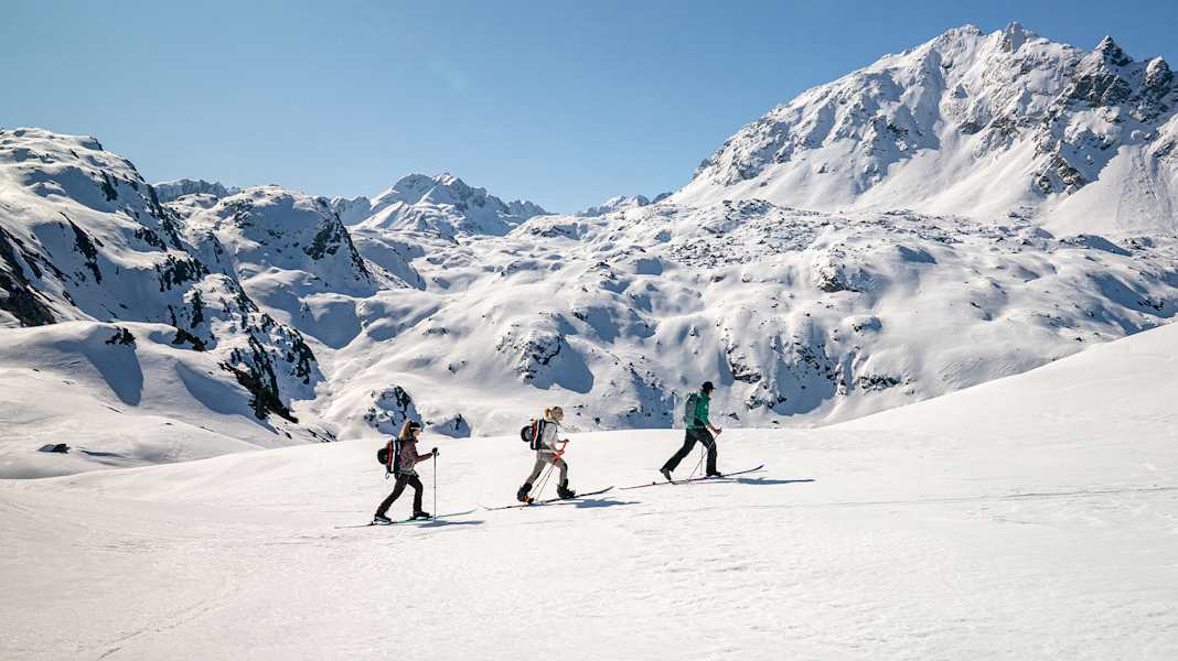Drei Skitourengeher begeben sich auf eine Tour auf unberührten Pfaden.