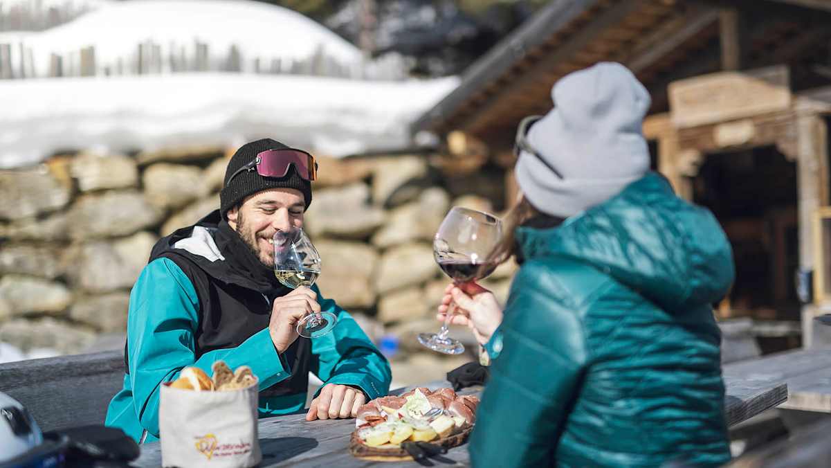Frau und Mann beim Einkehren auf einer urigen Hütte in Ratschings mit Jause und Wein.